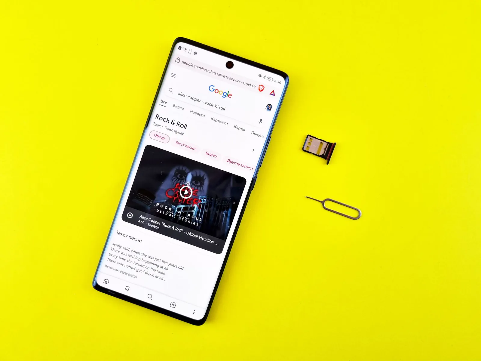 Smartphone on a desk with a SIM card and ejector pin beside it