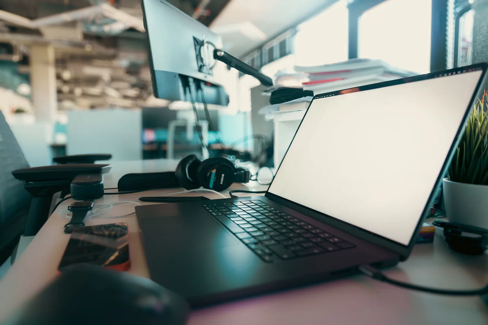 Contemporary office desk with laptop, monitor, and headphones
