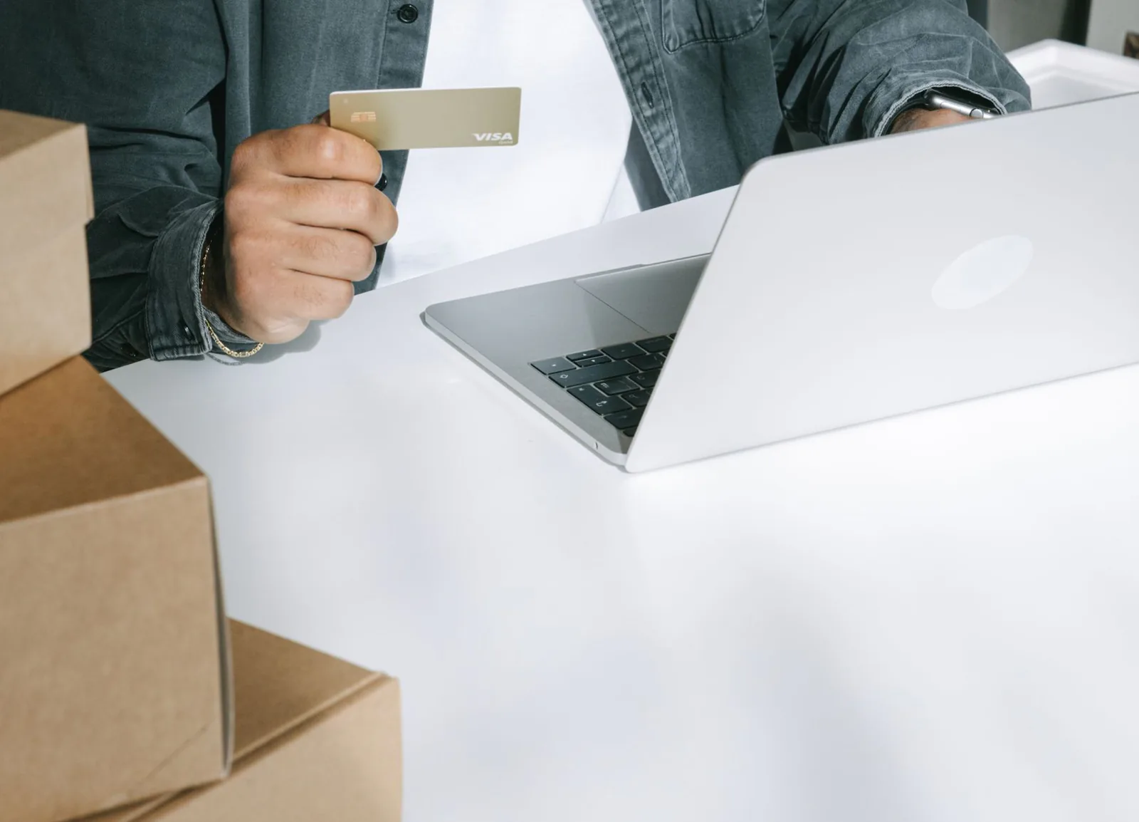 Person using a credit card for online shopping surrounded by shipping boxes